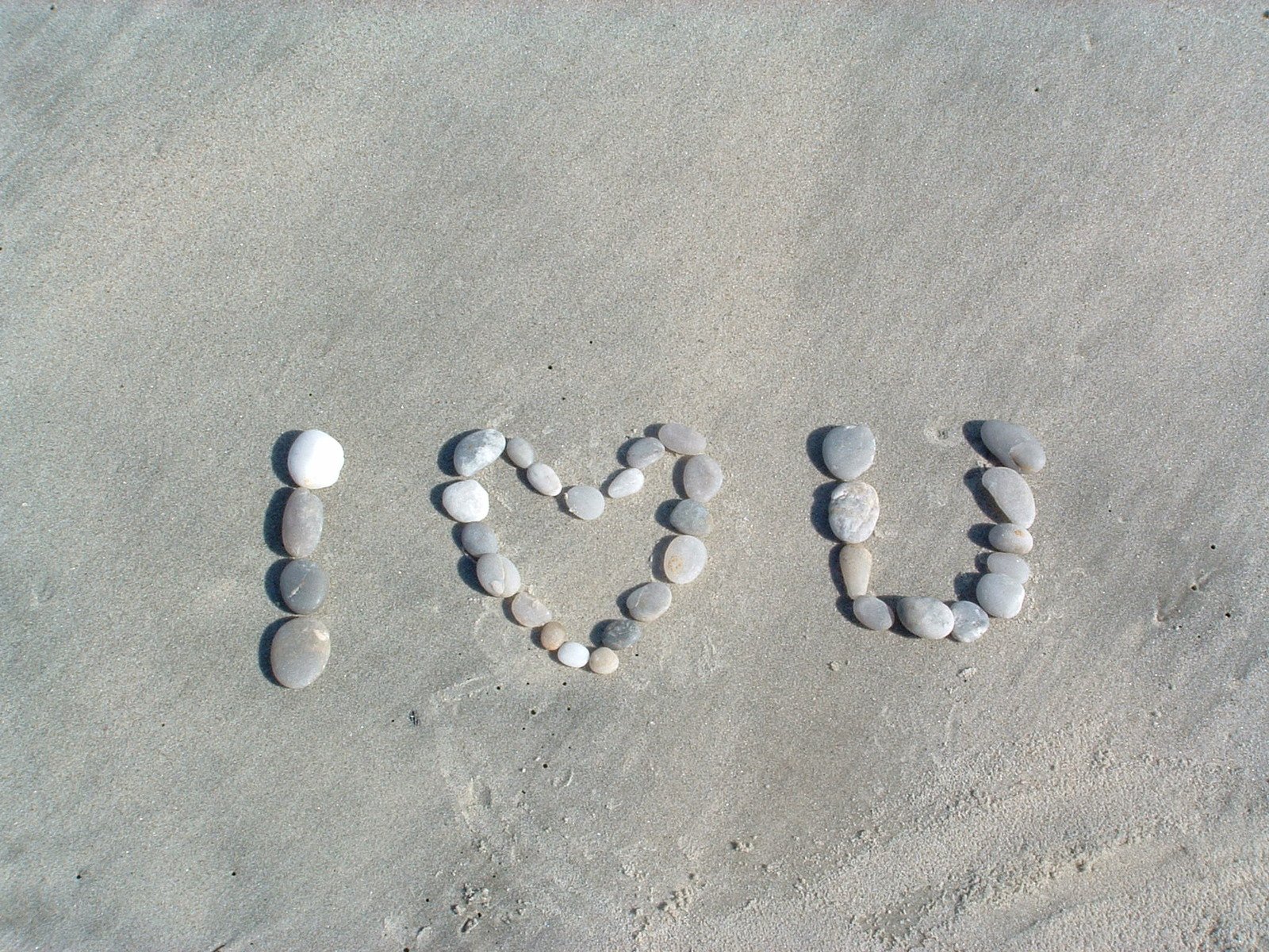 the word rock spelled with pebbles in a beach