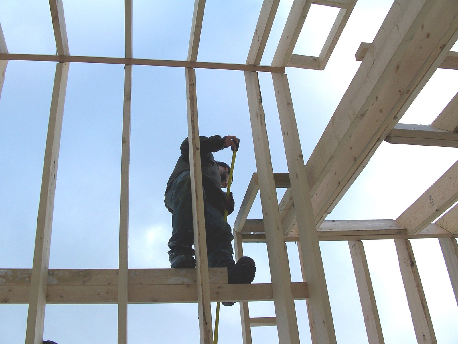 construction workers erecting rafters on wooden frame structure