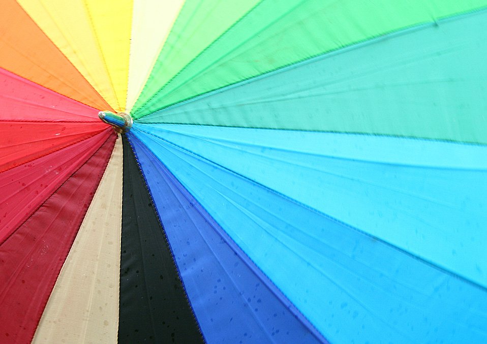 a bright rainbow colored umbrella is open to show the different colors