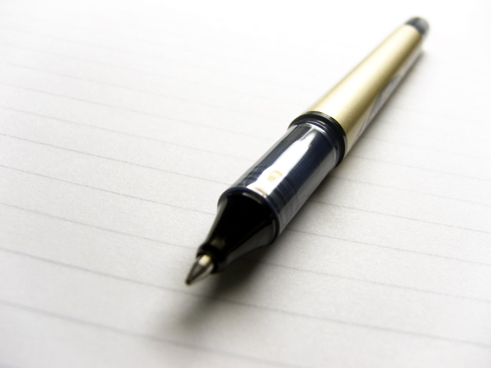 a fountain pen is resting on top of a lined notebook