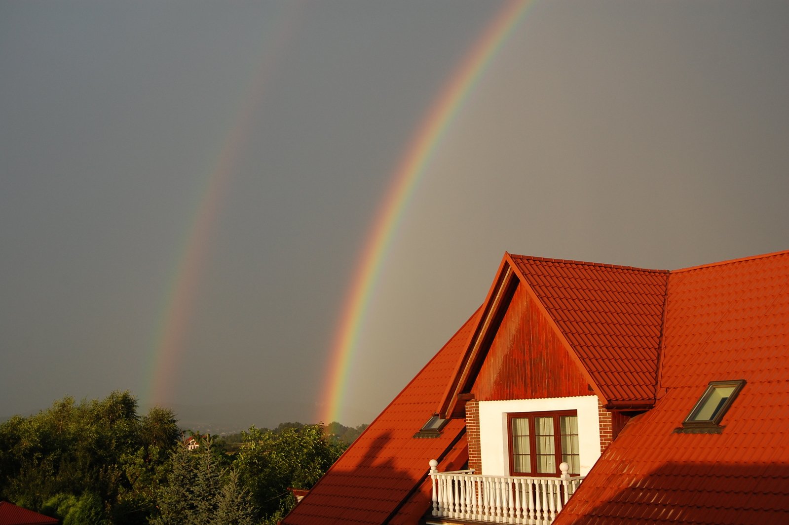 two rainbows above an empty house on a cloudy day