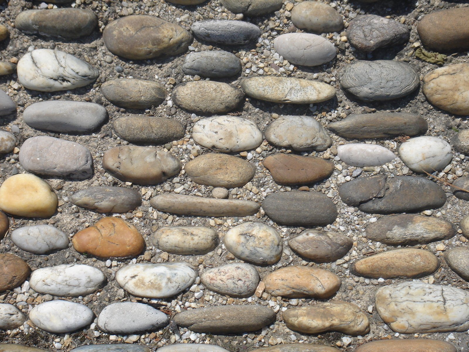 some rocks and gravel with different color stones and one rock is in the background