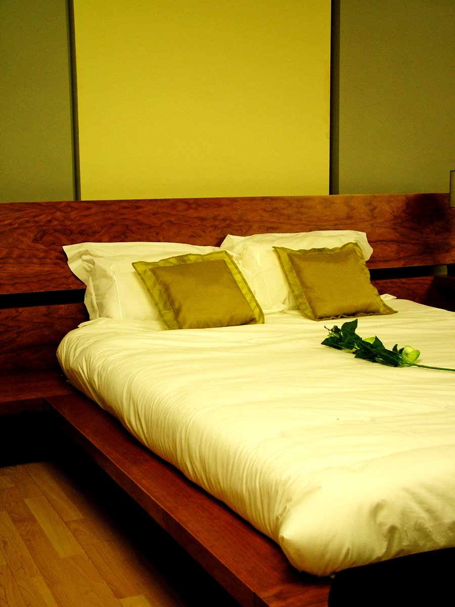white bedspread with flower decoration on wooden bed