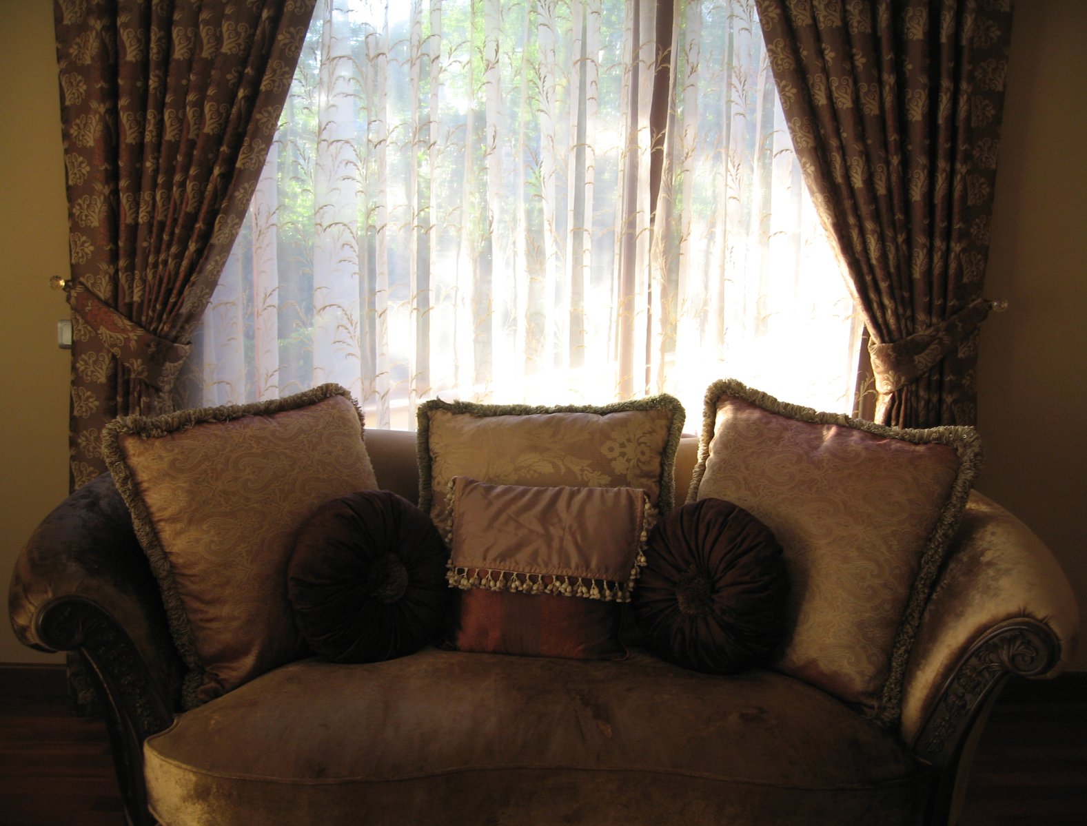 a sofa sitting in front of a window filled with pillows