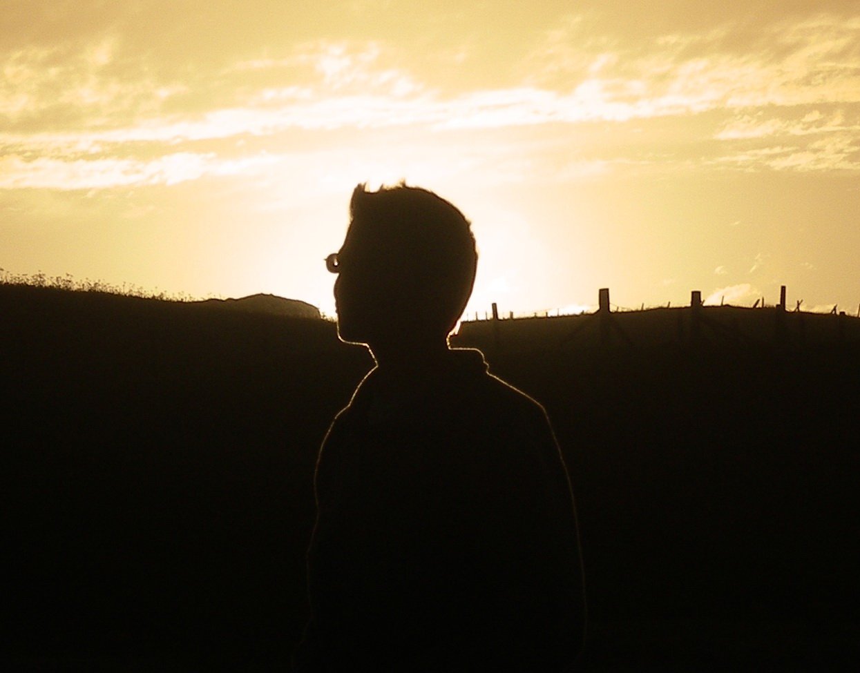 a man is seen standing in the shadow of a sunset