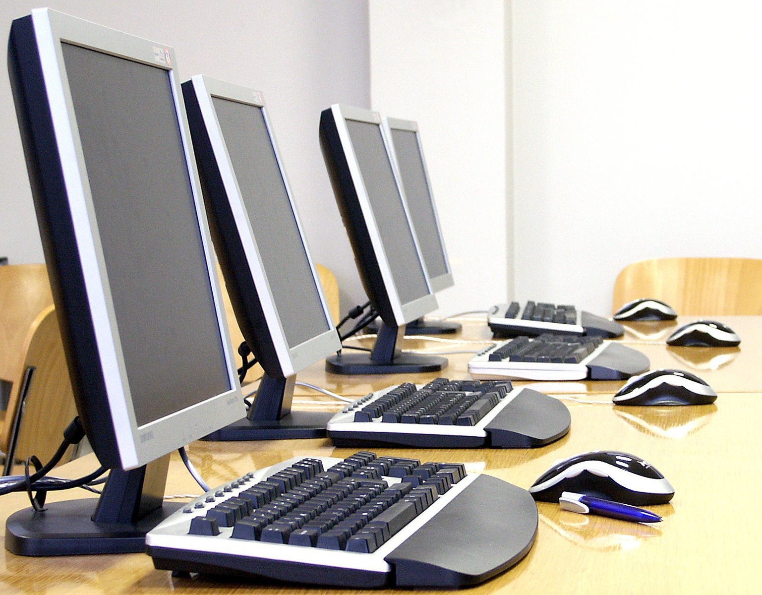 three computer monitors with keyboards and mouses on top