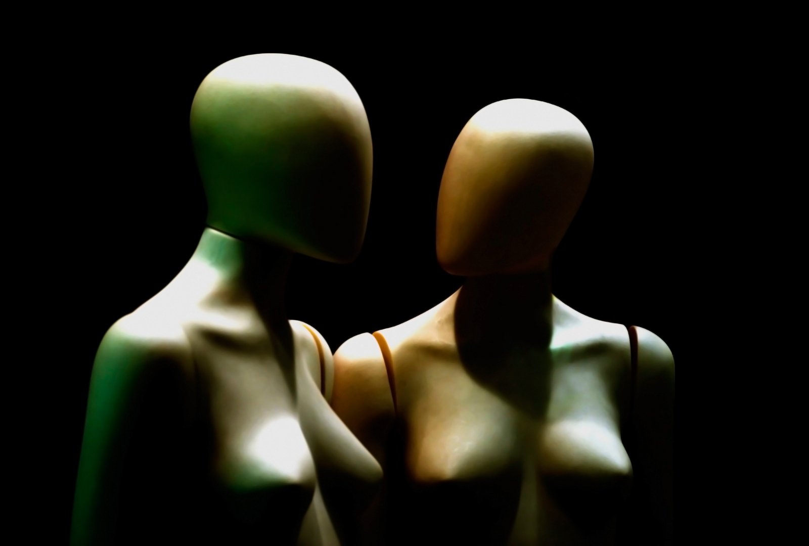 two female mannequins facing each other against a black background