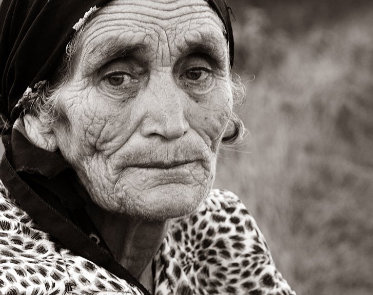 an old woman wearing head scarves and a leopard coat