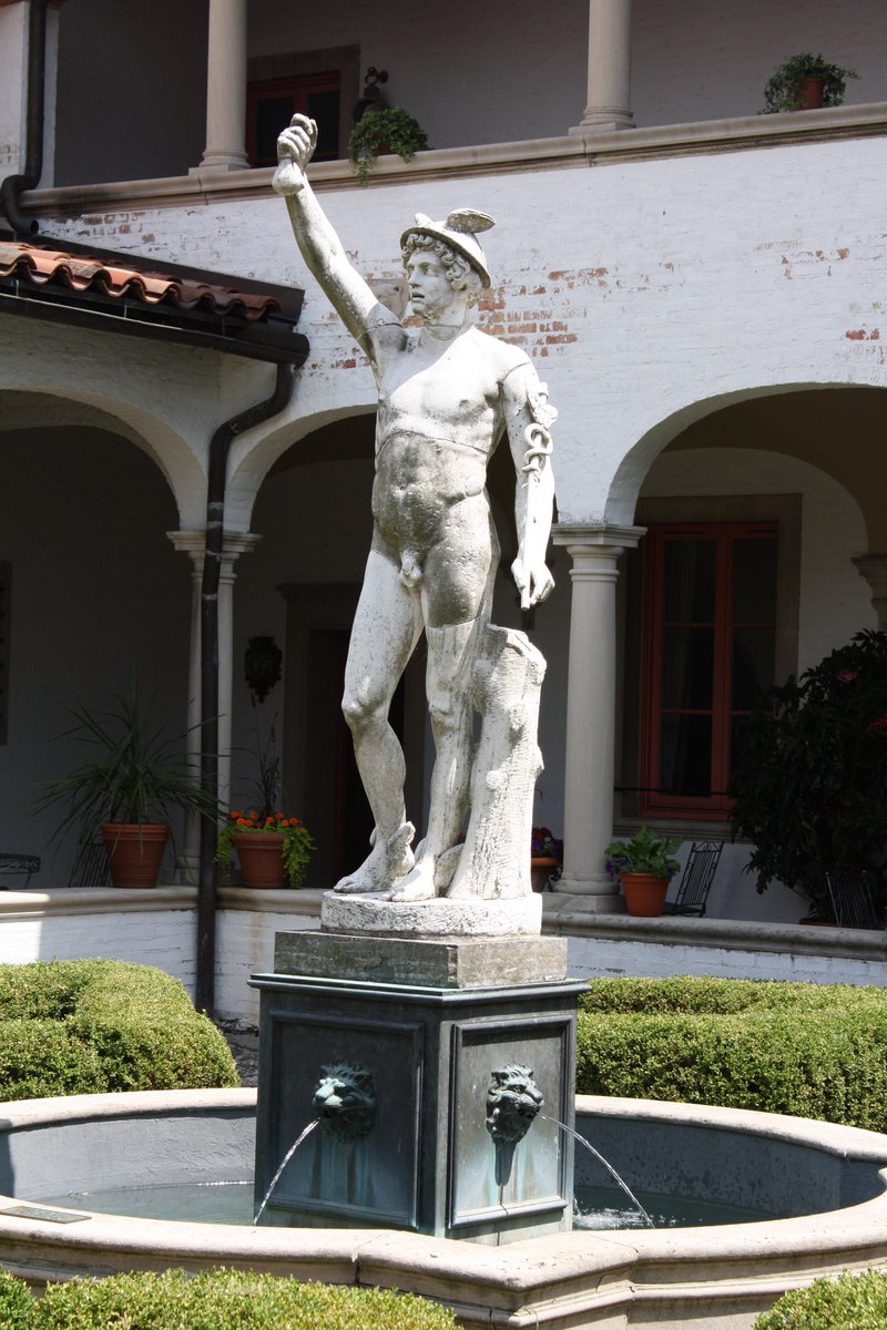 a sculpture of a man holding a hat in a courtyard
