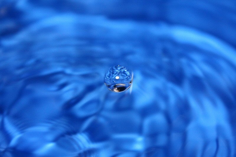 a blue water drop with another drop in the background