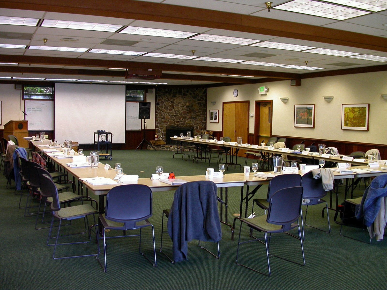 a large table set for a conference and a projection screen in the back