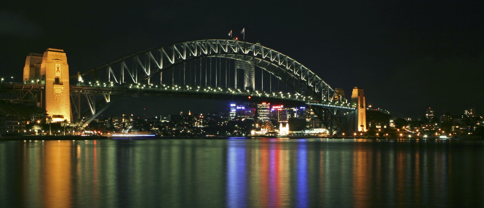 a nighttime s of a bridge with buildings reflected in it