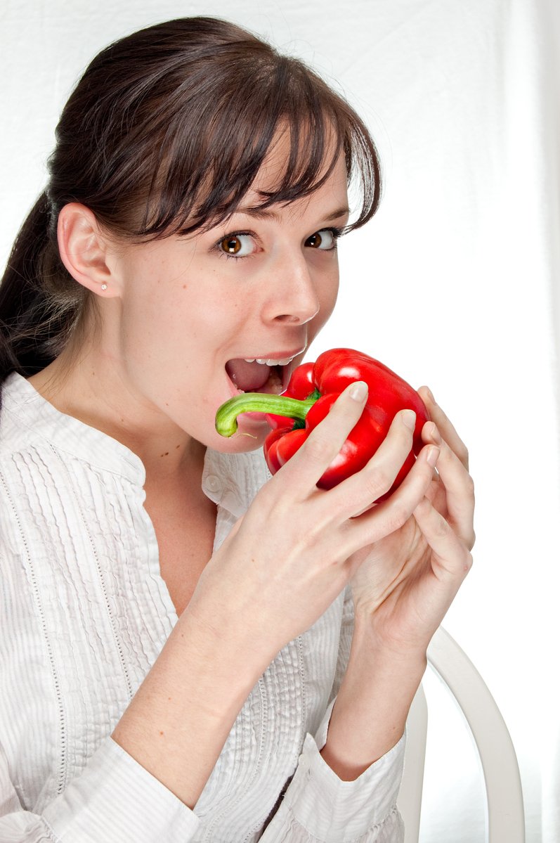 a woman is taking a bite out of a stuffed pepper