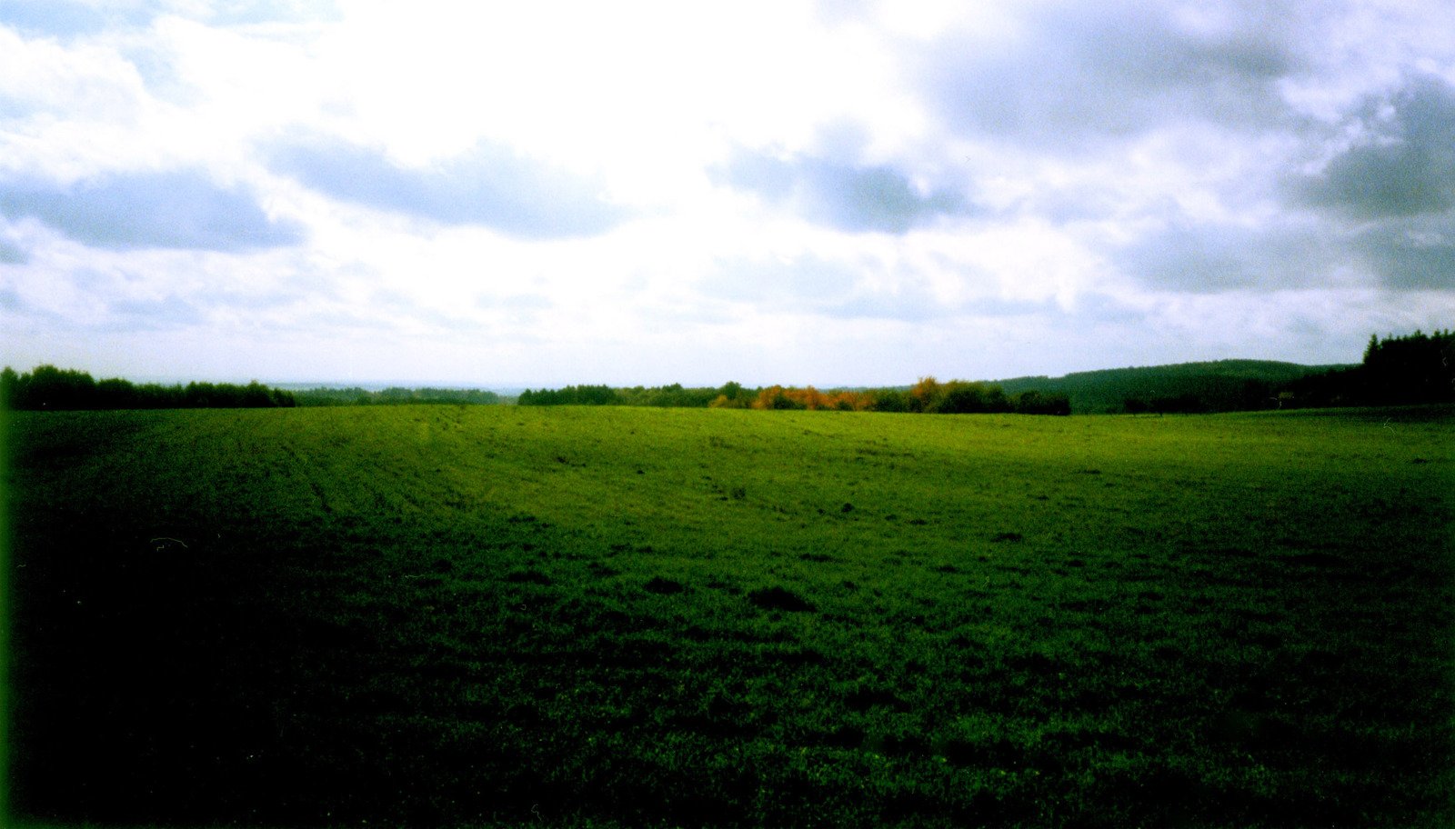 a view over a grassy field with sky in the background