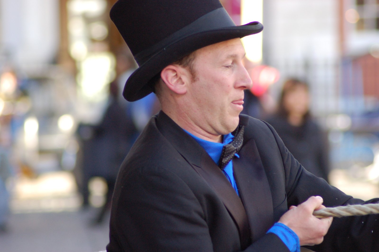 man wearing a top hat holds his cane in his right hand