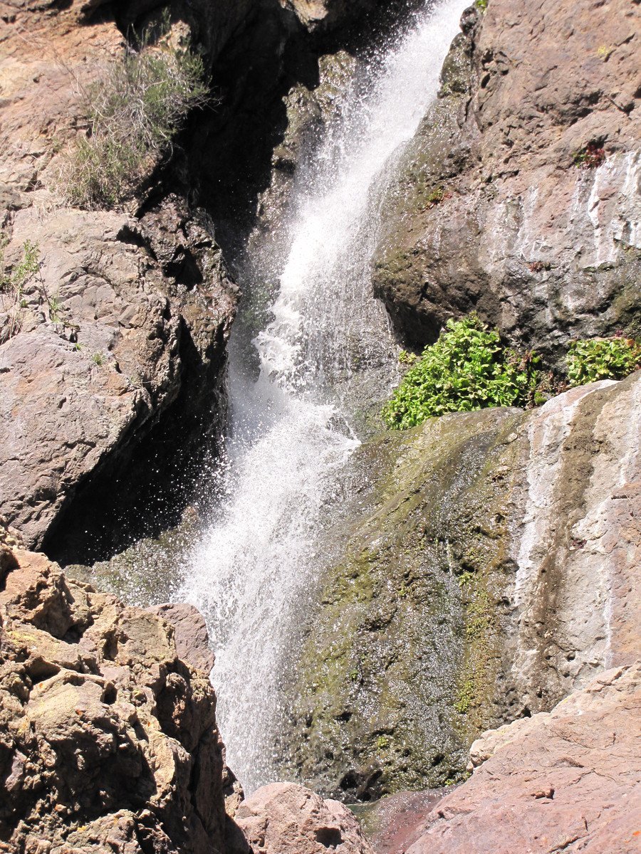 a small waterfall is near a large rock