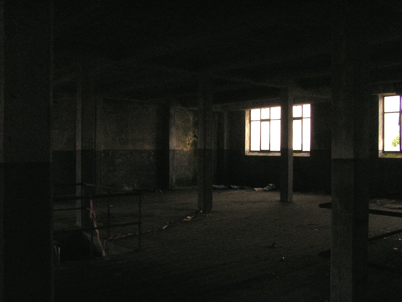 a dark room with two windows on the walls