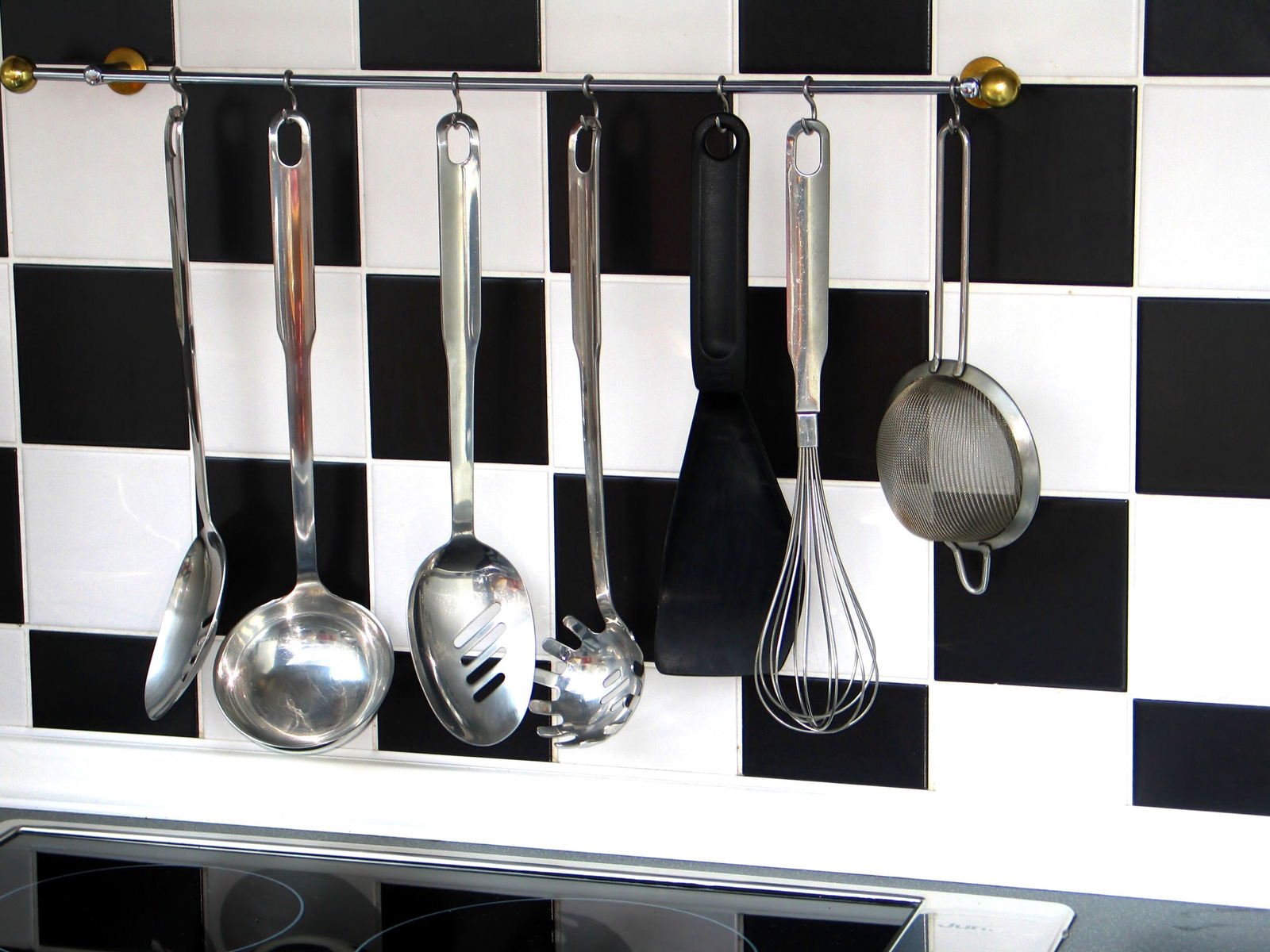 kitchen utensils hanging on a wall and checkered tiles