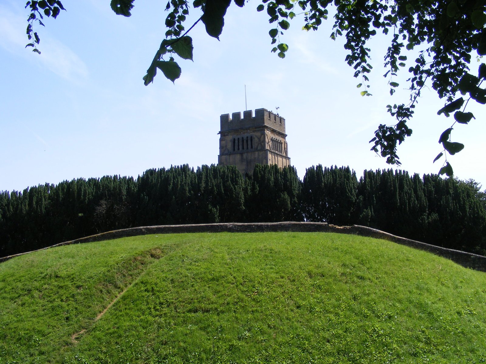 a tall tower building sitting on top of a grass covered hill
