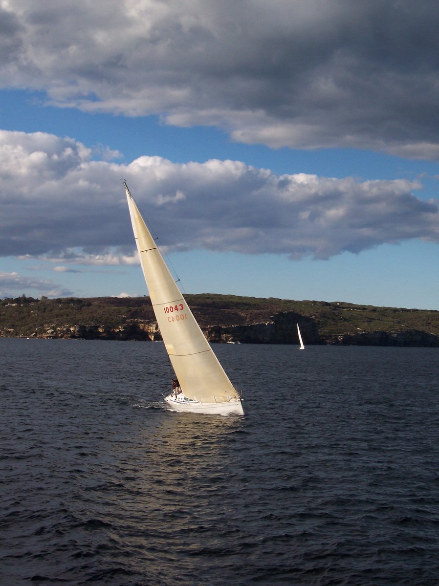 a sail boat riding in the ocean with one sail