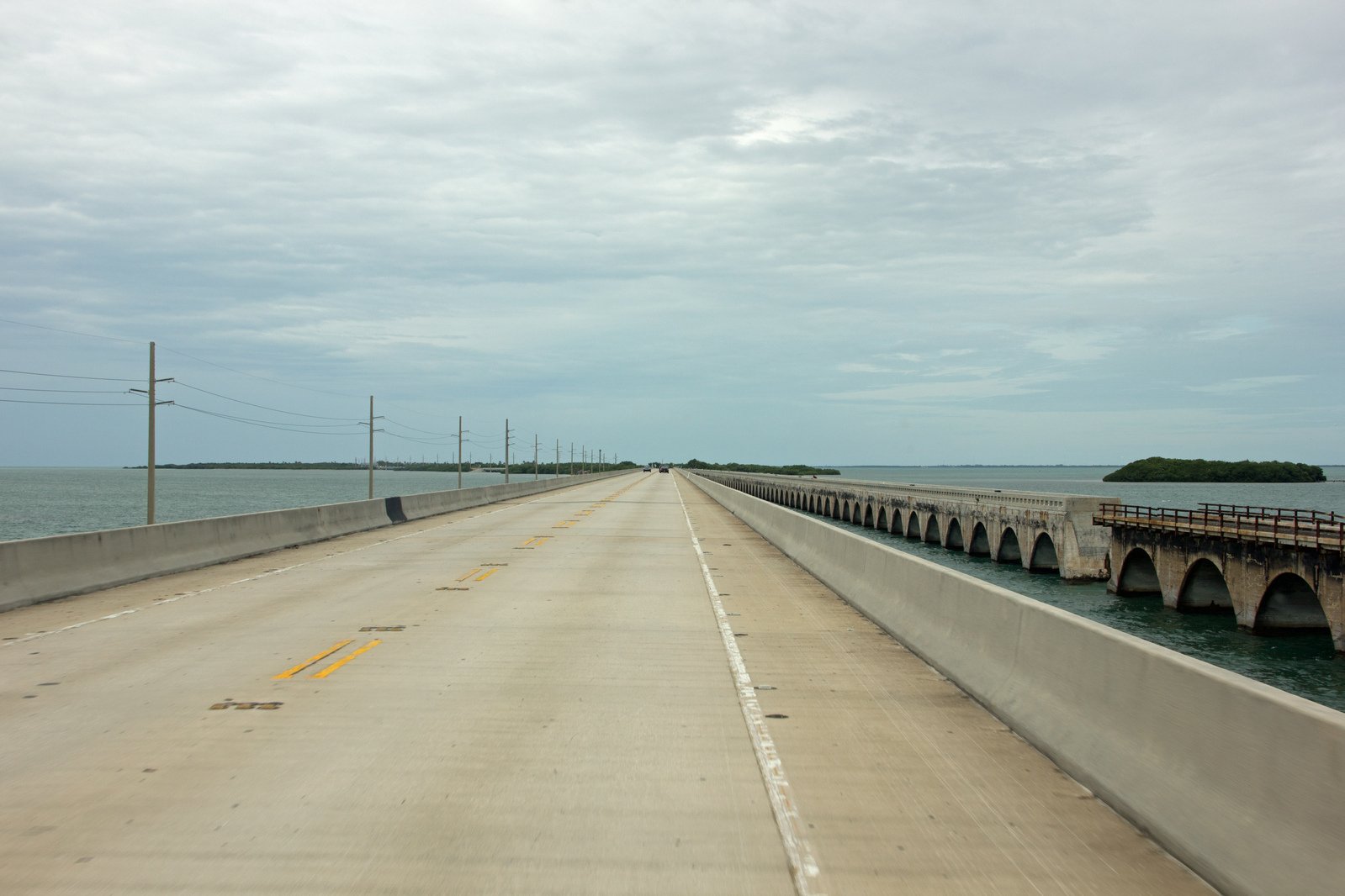 a road along an ocean with two large bridges