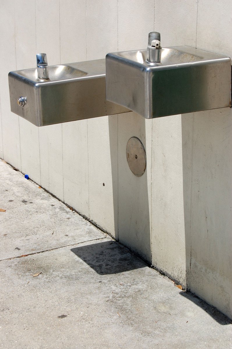 two shiny metallic hand bars near wall with water