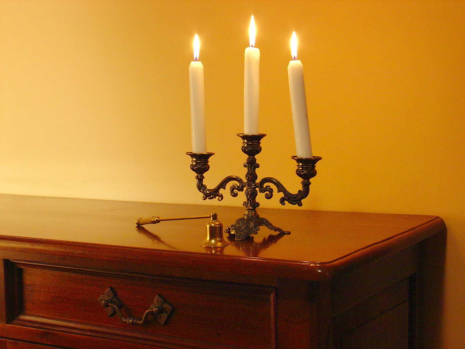 an elegant candela with three candles sits on top of a dresser