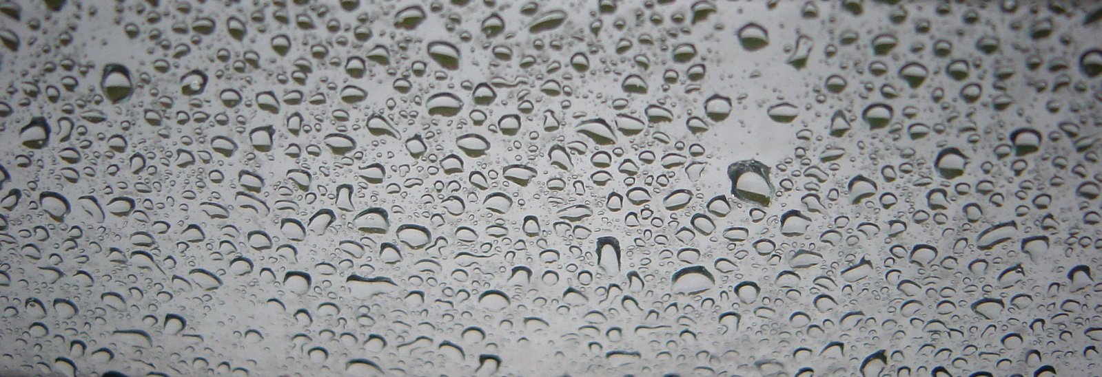 rain drops sit on the window glass as it rains