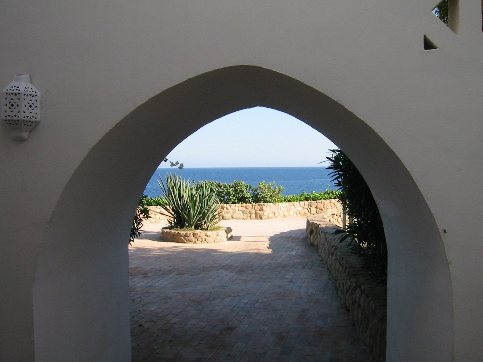 an archway with a bench on the other side leads to the beach