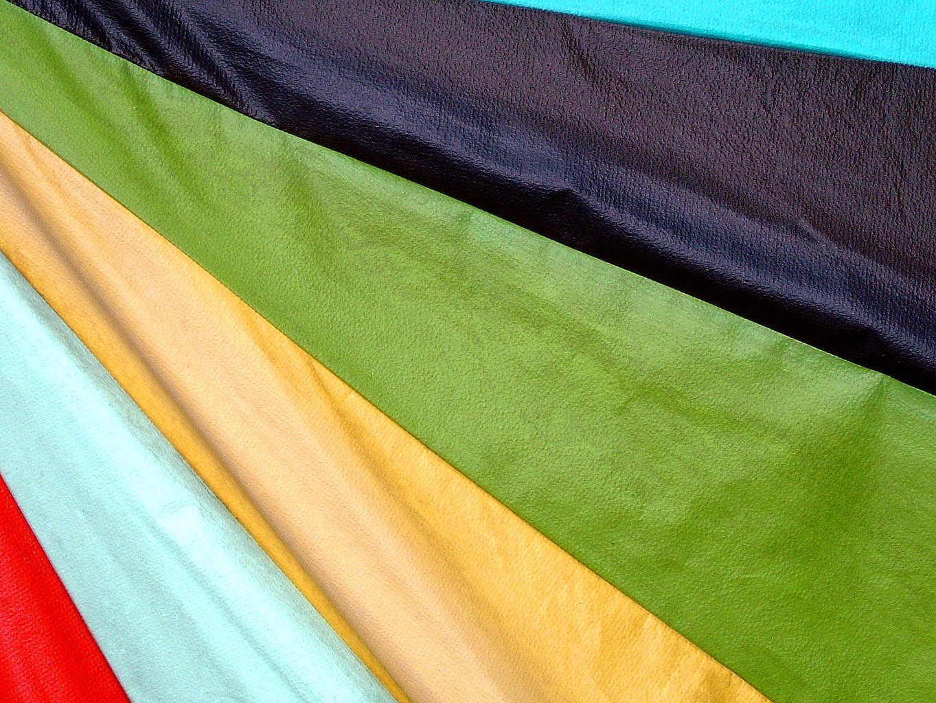 a collection of different colored material on a bed
