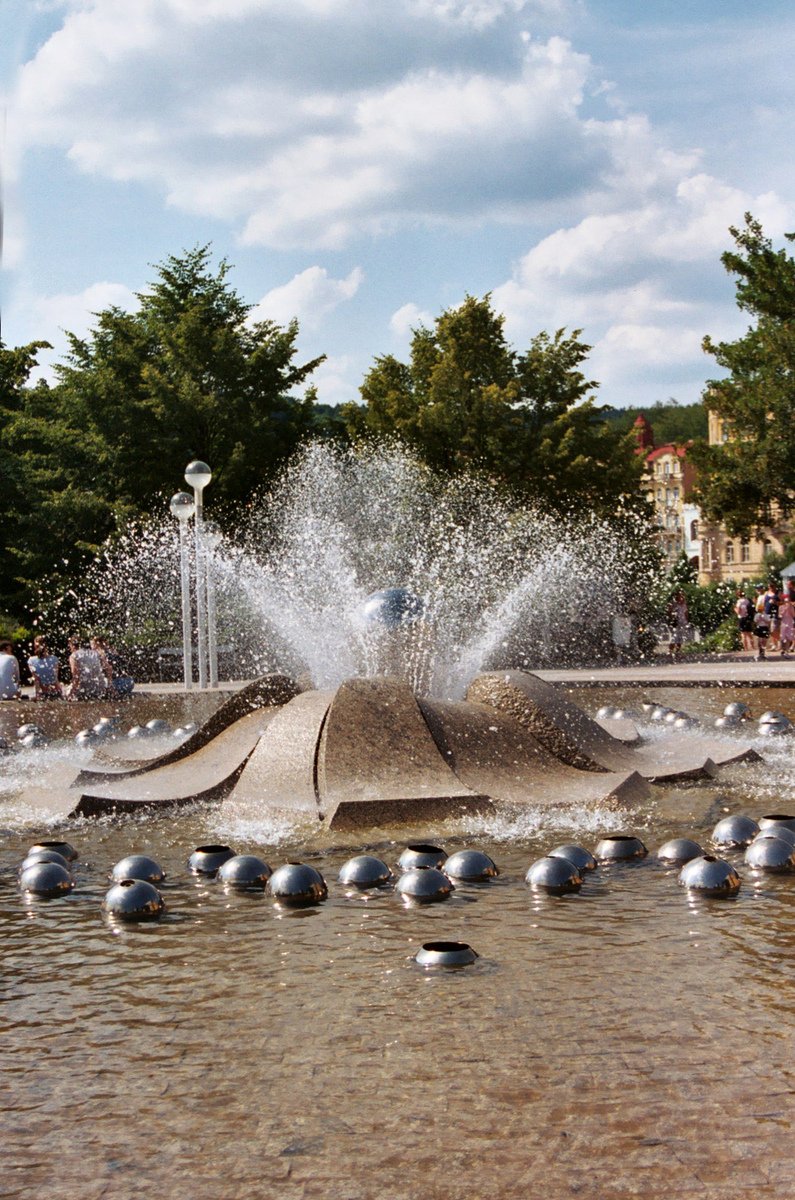 a big fountain covered in water surrounded by ducks