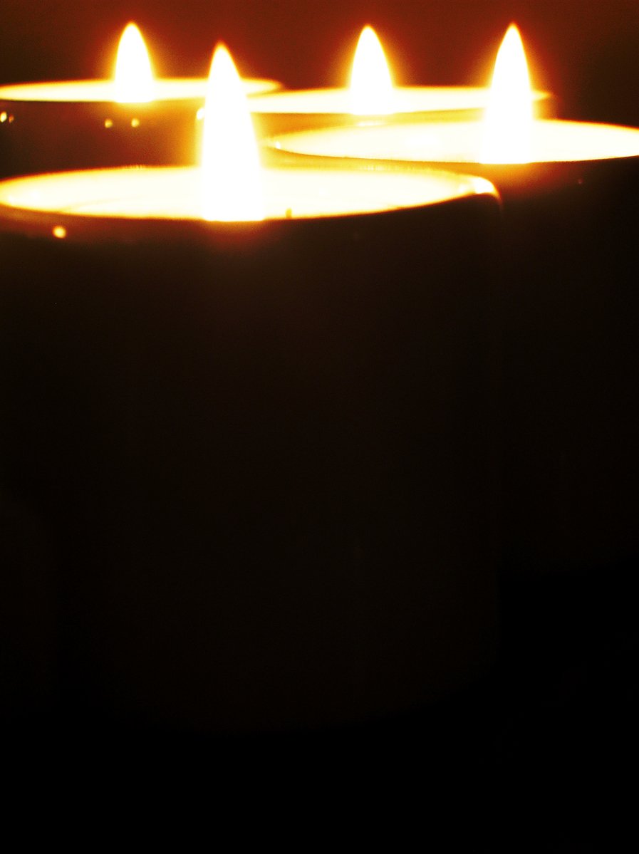 four lit candles in the dark on a counter