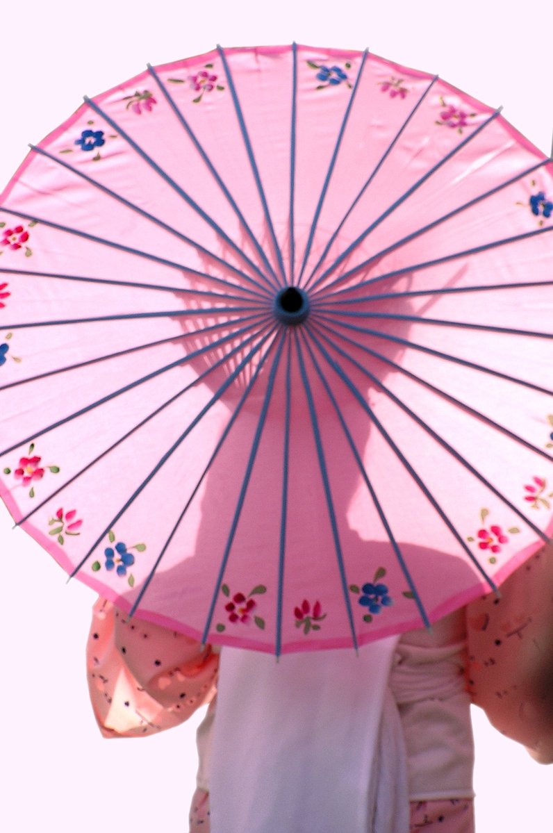 a pink and blue umbrella with a person's arm extended to it