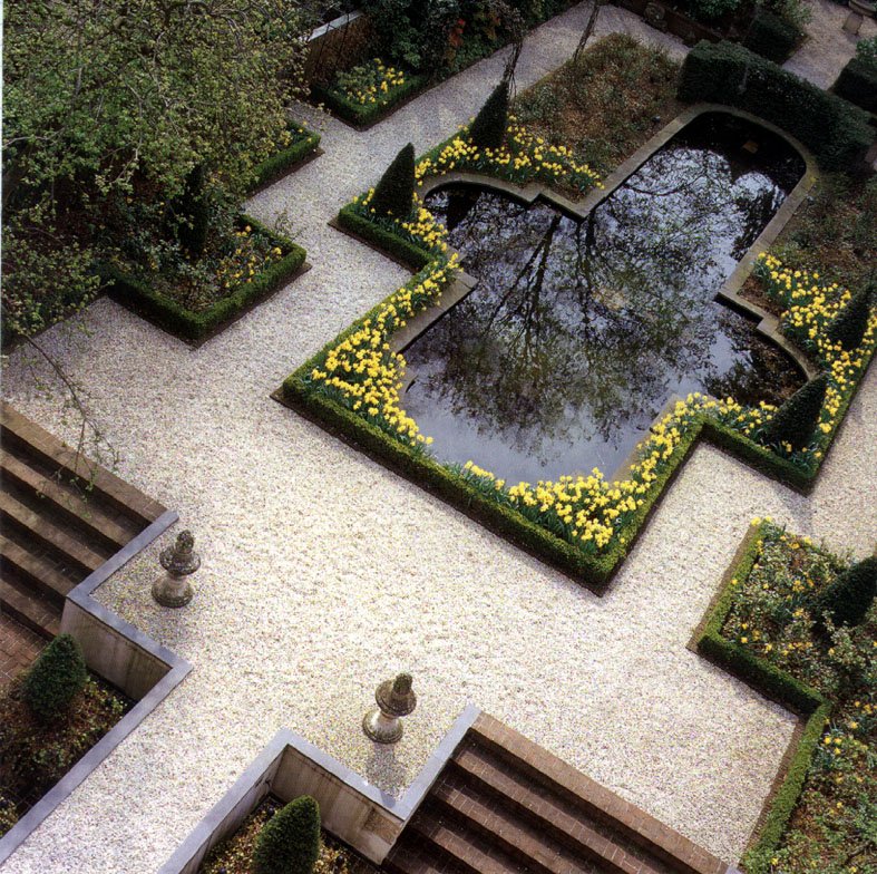 an outdoor space with steps, flowered shrubs and water in the center