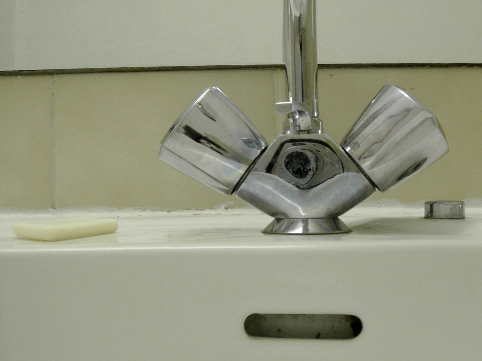 a close up of a sink faucet with a soap dish underneath