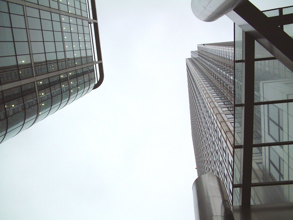 two skyscrs with windows and some very cloudy sky