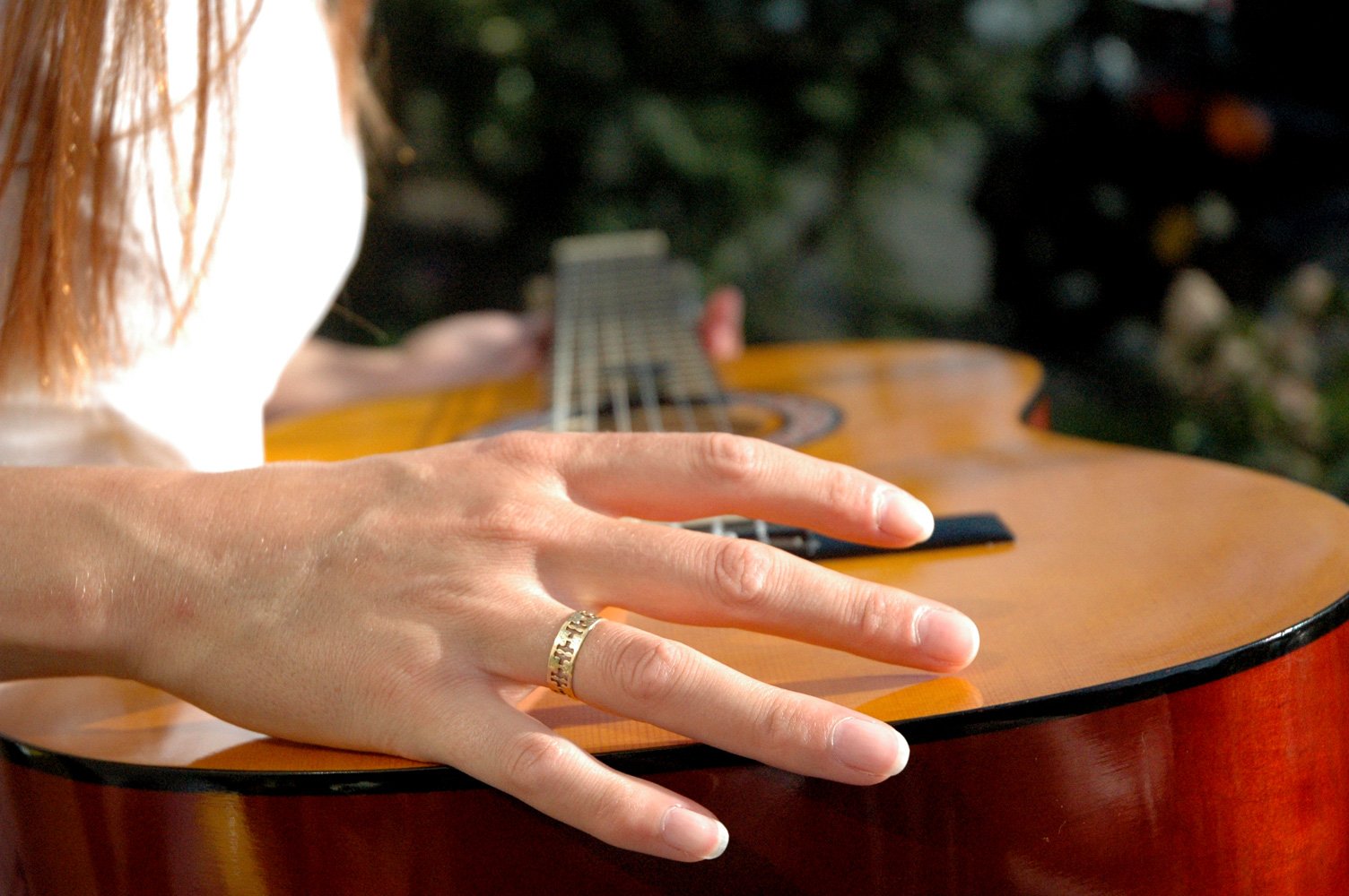 a person wearing a ring with their hand on top of an acoustic guitar