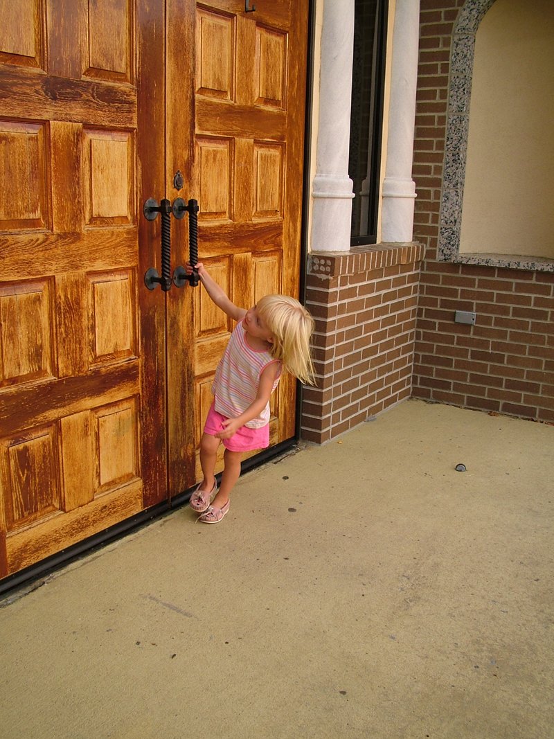 a girl with her arm around a wooden door