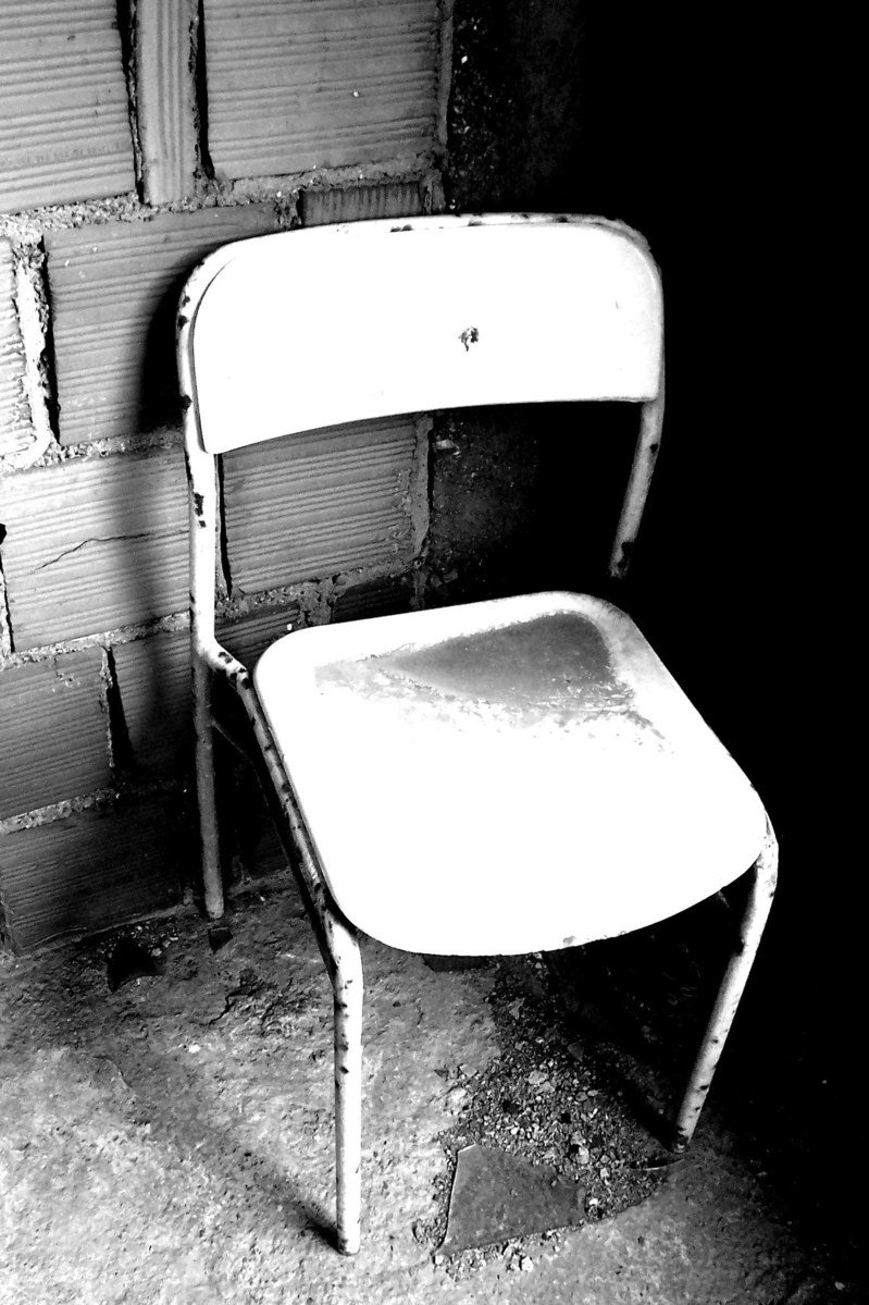an old worn chair against a brick wall