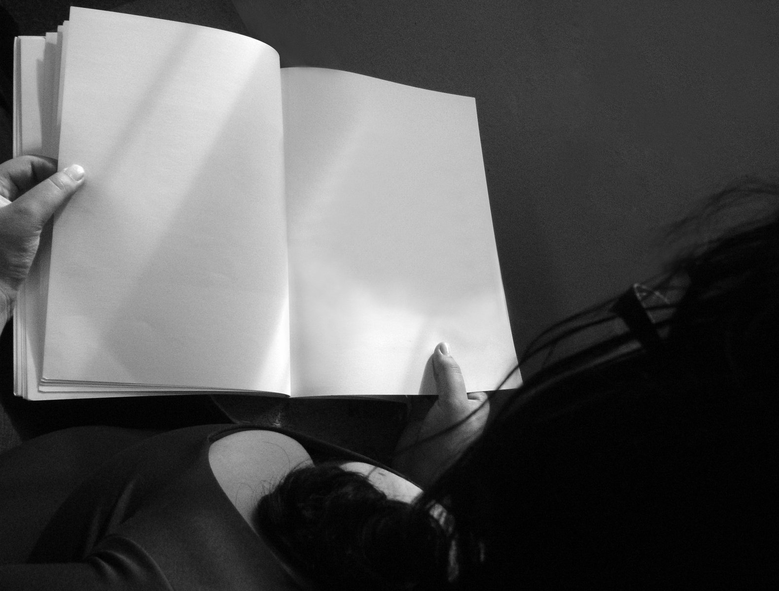 a person's arm resting on their knees holding a book in their left hand