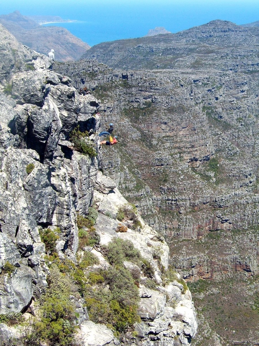 the rocky cliff is surrounded by many trees and mountains