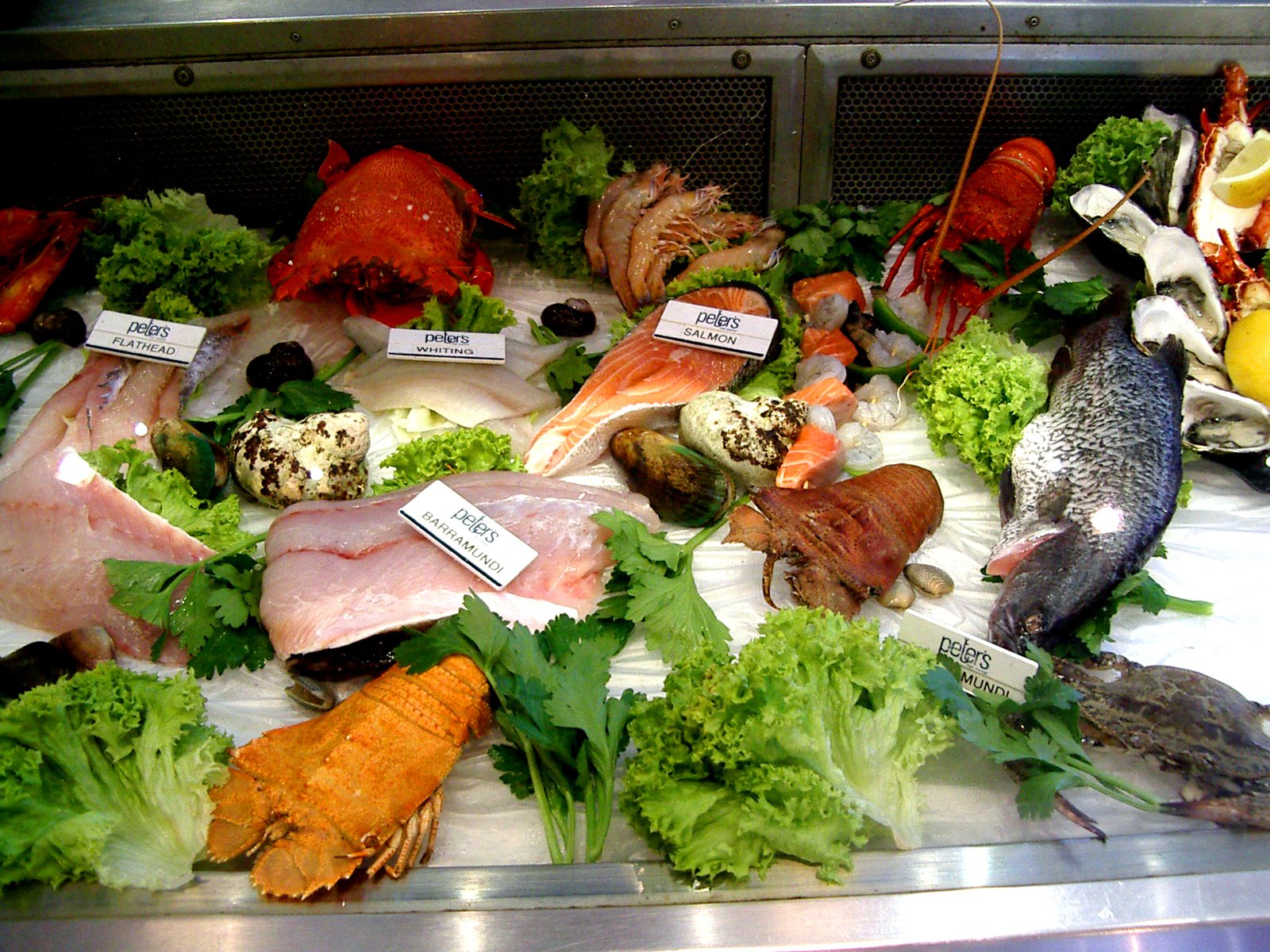 food is displayed on a plate near other vegetables and fish
