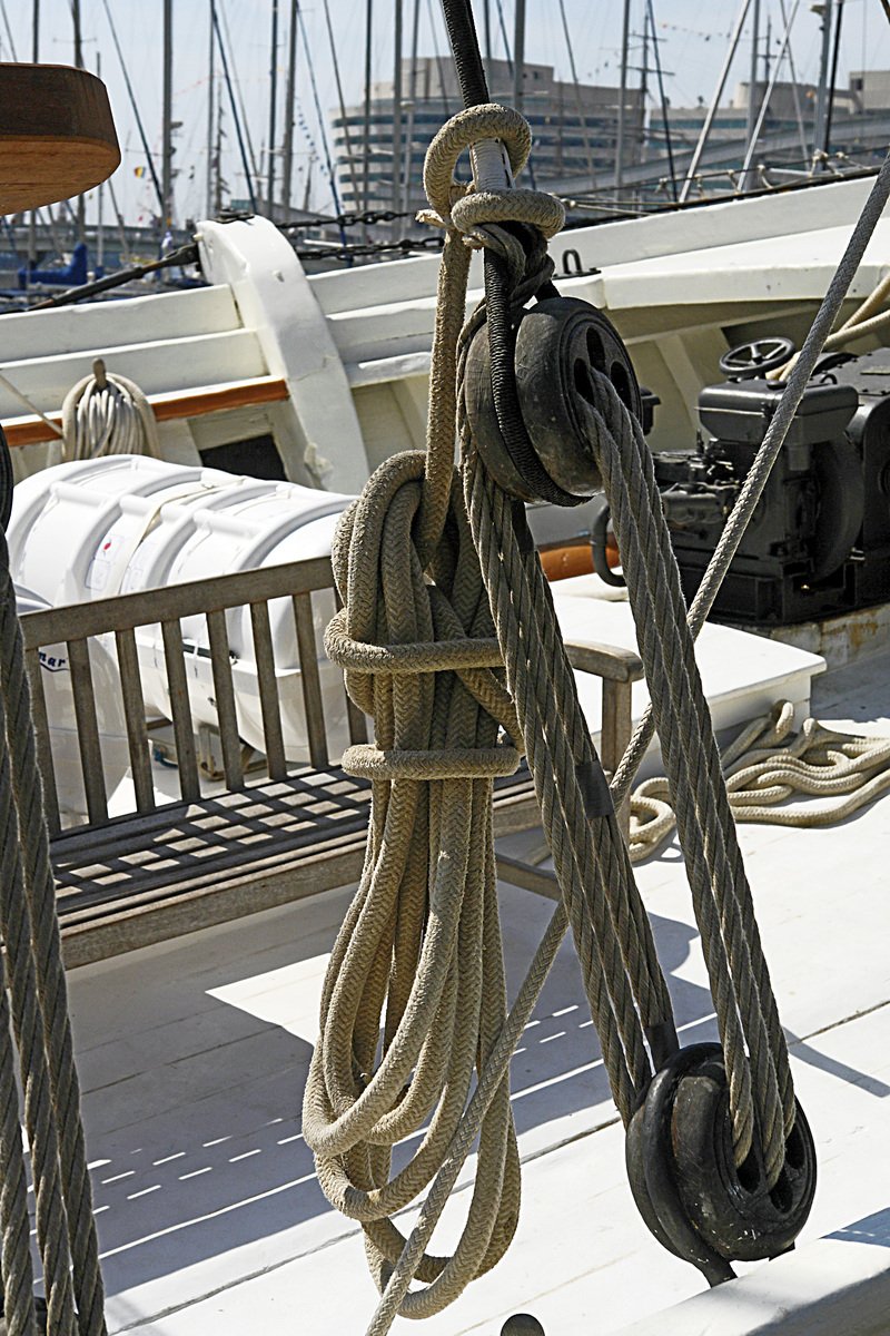 ropes are hanging from a boat with other boats in the background