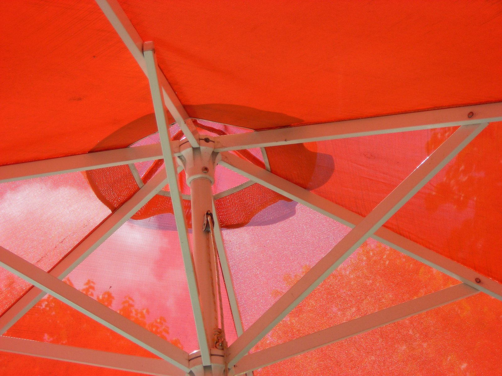 a red and yellow umbrella is open on a sandy beach