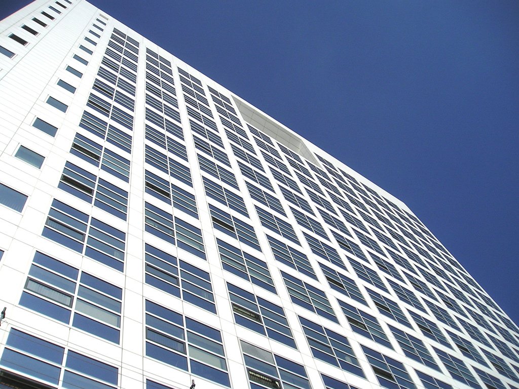 a high rise building with windows against a clear blue sky