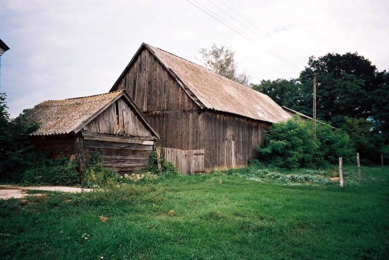 an old barn sitting in a green field
