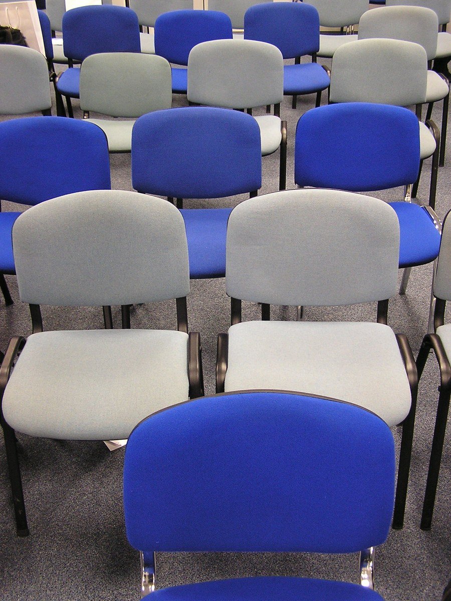 rows of blue and gray chairs sit in the middle of an empty room