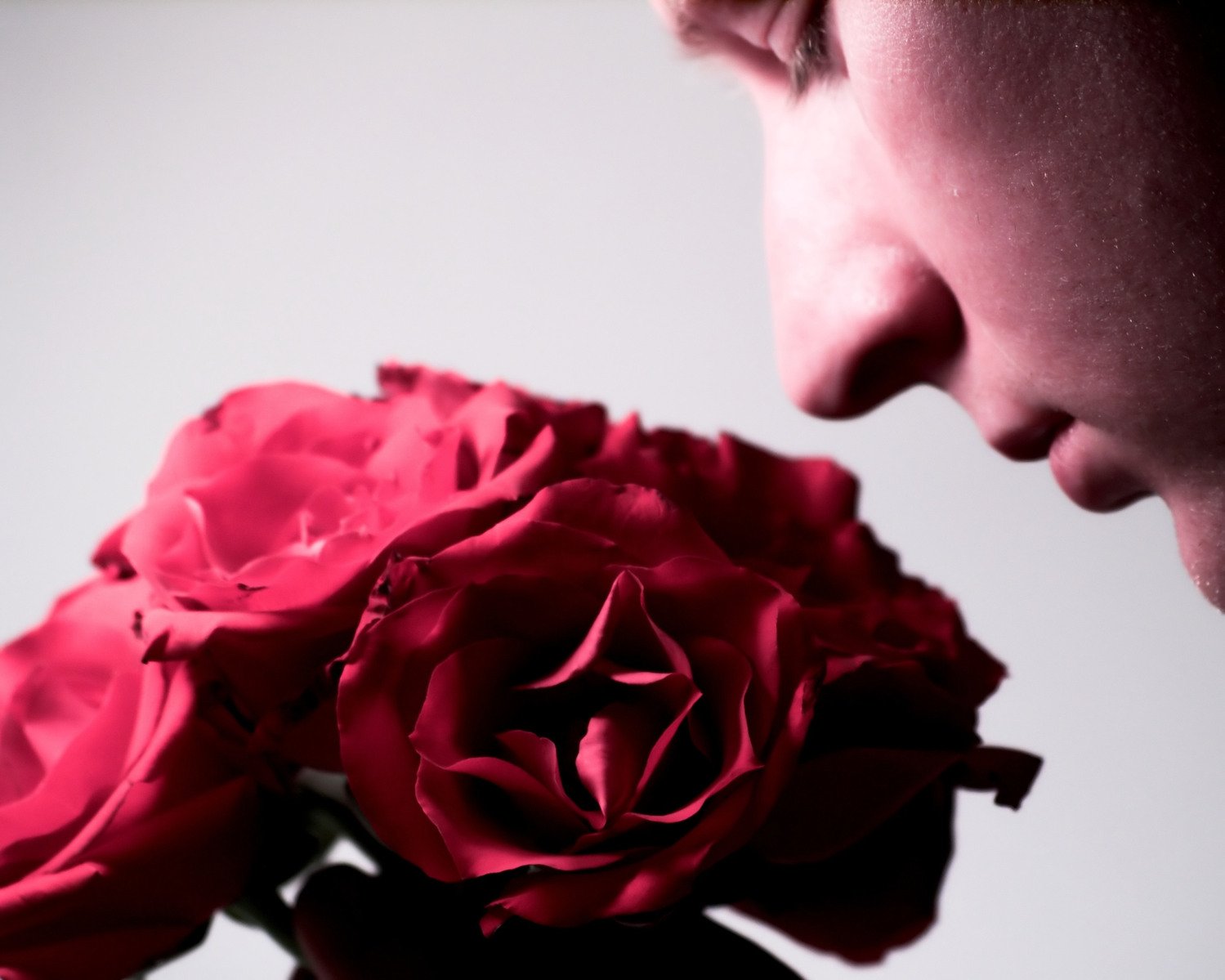 a woman kissing a rose next to another red rose
