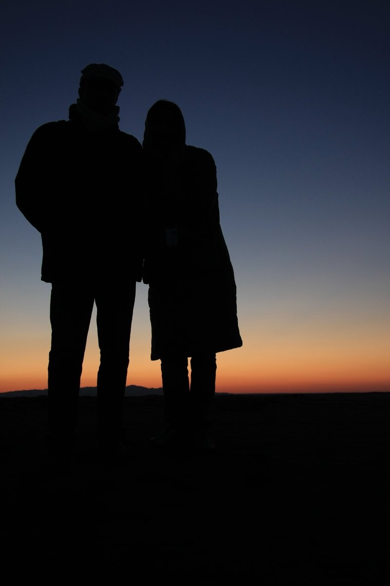 silhouette of a couple on the ground with a setting sun behind them