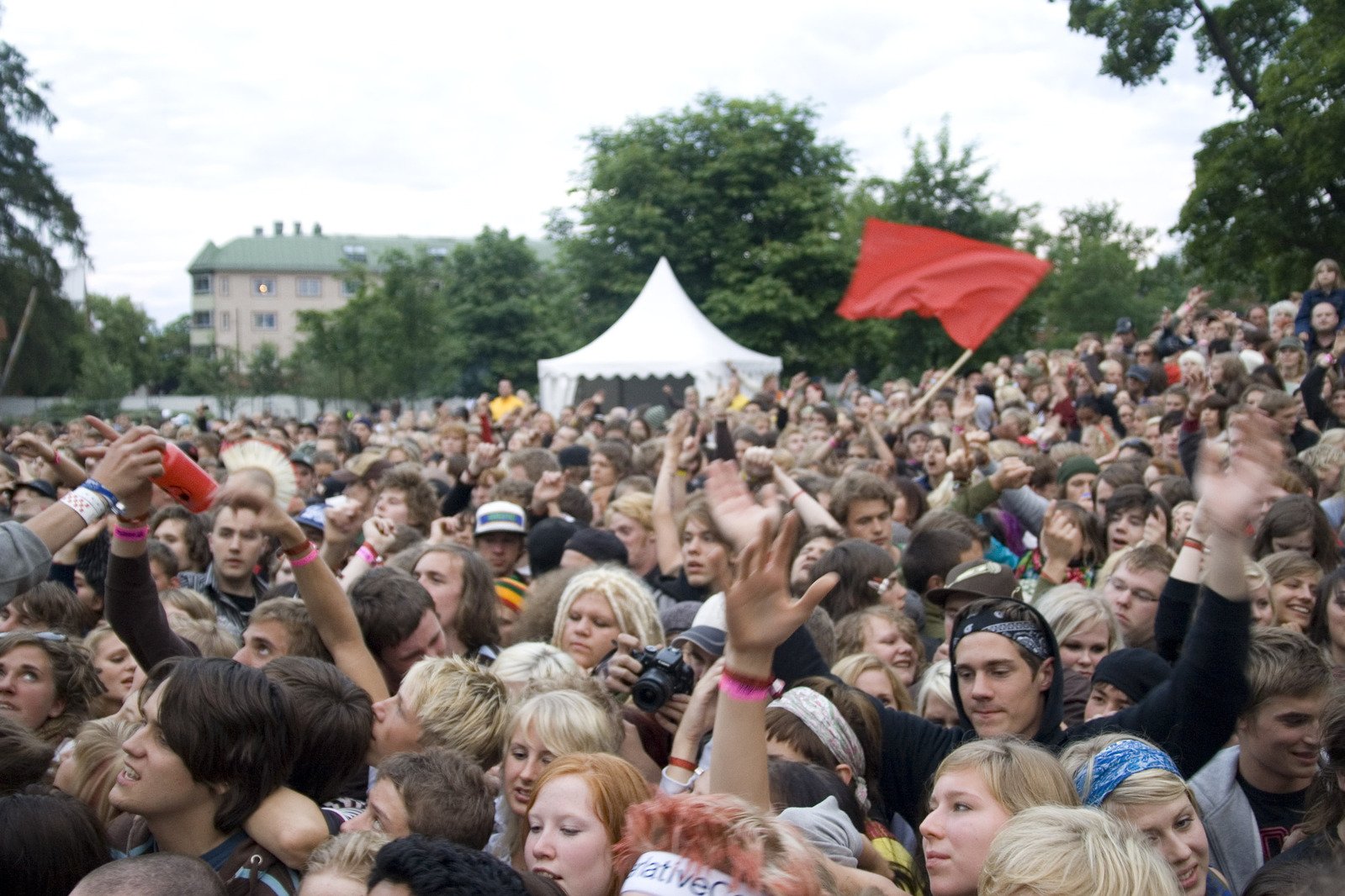 a large crowd of people gathered to watch a red flag